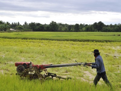 Boer ploegt rijstveld met een kleine tractor in Cambodja tijdens de 21-daagse route Cambodja en Thailand.