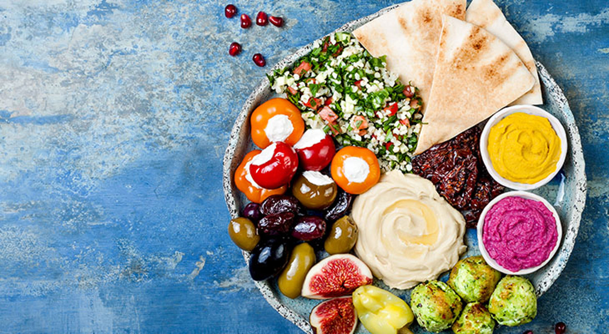 Vegetarisch Jordaans gerecht Mediterrane mezze-schotel met hummus, tabouleh, pita, olijven, falafel en dips op blauwe achtergrond.