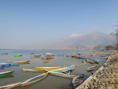 Kleurrijke bootjes op het Phewa-meer in Pokhara, met de Himalaya op de achtergrond.