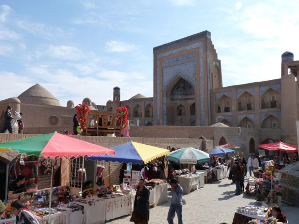 Markt met kleurrijke kraampjes voor een historisch complex in Oezbekistan tijdens een groepsrondreis.