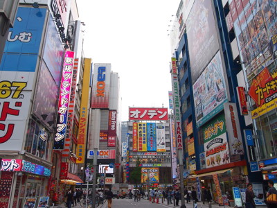 Drukke straat in Akihabara, Tokio, met kleurrijke neonreclames en elektronicawinkels.