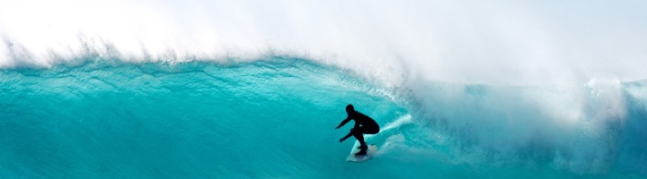 Surfer rijdt door een hoge golf bij Kaapstad.