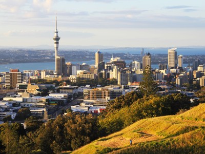 Uitzicht op de skyline van Auckland met de Sky Tower, gezien vanaf een groene heuvel.