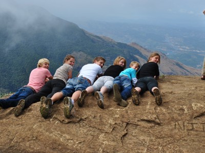 Groep reizigers ligt op een rotsplateau met uitzicht op de bergen tijdens de Route Sri Lanka.