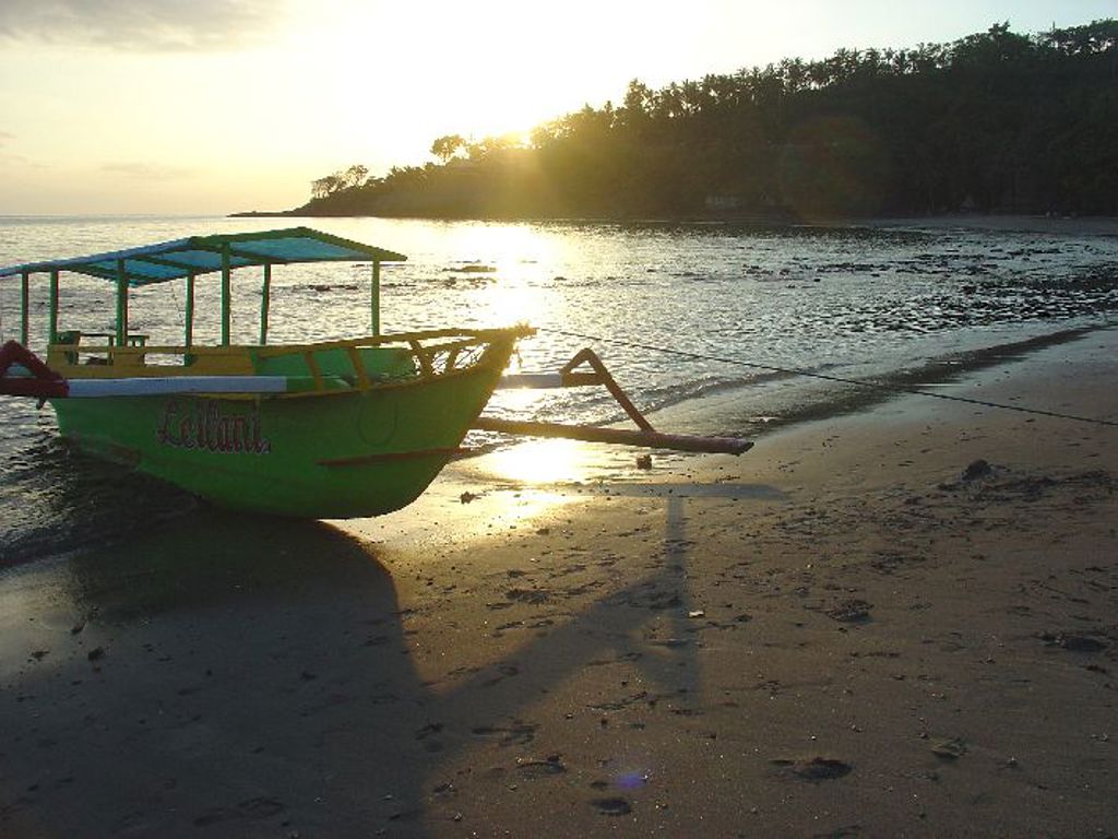 Traditionele boot op het strand bij zonsondergang tijdens groepsrondreis Java, Bali en Lombok.