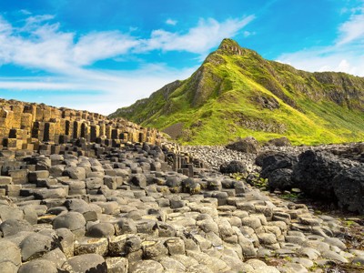 Basaltzuilen van Giant’s Causeway aan de kust van Noord-Ierland, met groene heuvels op de achtergrond.