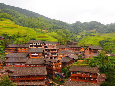 Traditionele houten dorpshuizen tussen groene rijstterrassen in de bergen van China tijdens groepsrondreis China.