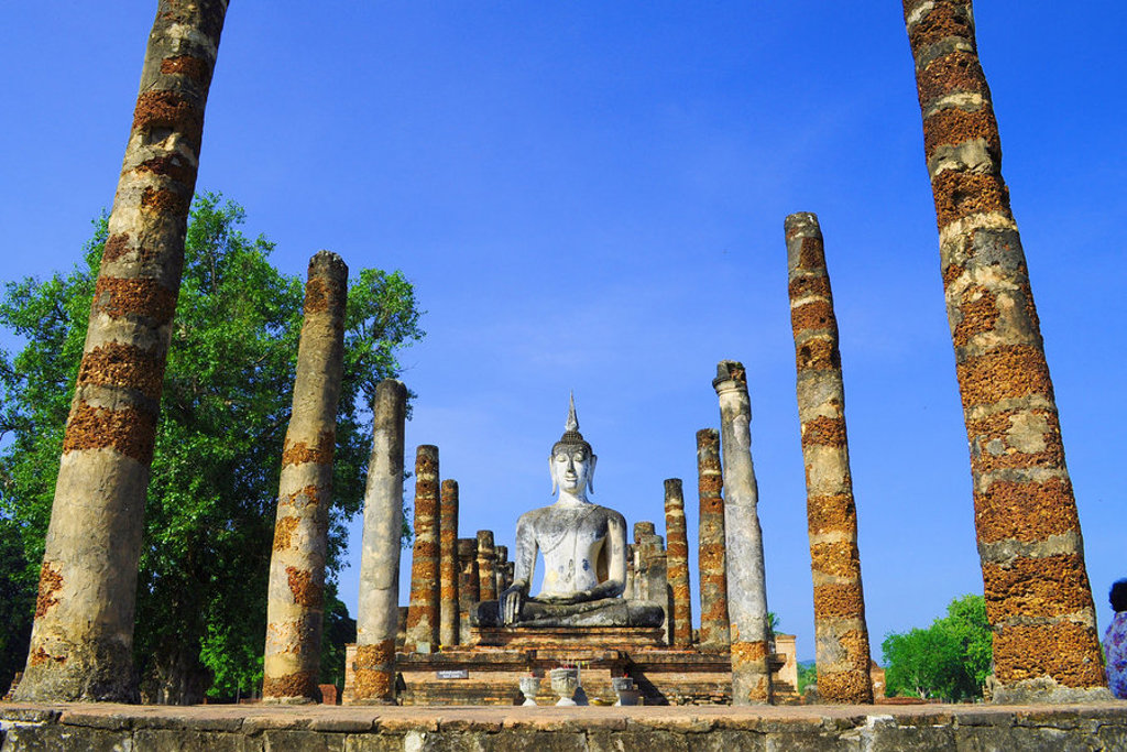 Boeddhabeeld tussen tempelpilaren in het historische park van Sukhothai, Thailand.