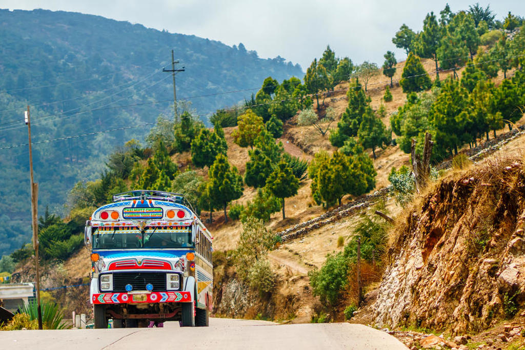 Kleurrijke chickenbus op bergweg in Guatemala tijdens familiereis Guatemala en Belize.