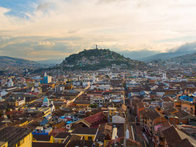 Uitzicht over de historische binnenstad van Quito met de heuvel El Panecillo bij zonsondergang.