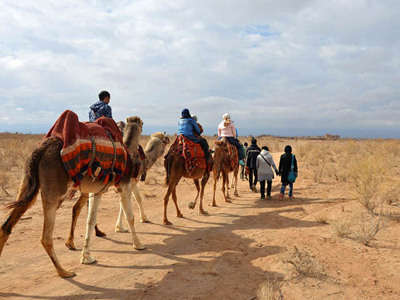 Karavaan met reizigers op kamelen door de woestijn tijdens de 19-daagse route door Iran.