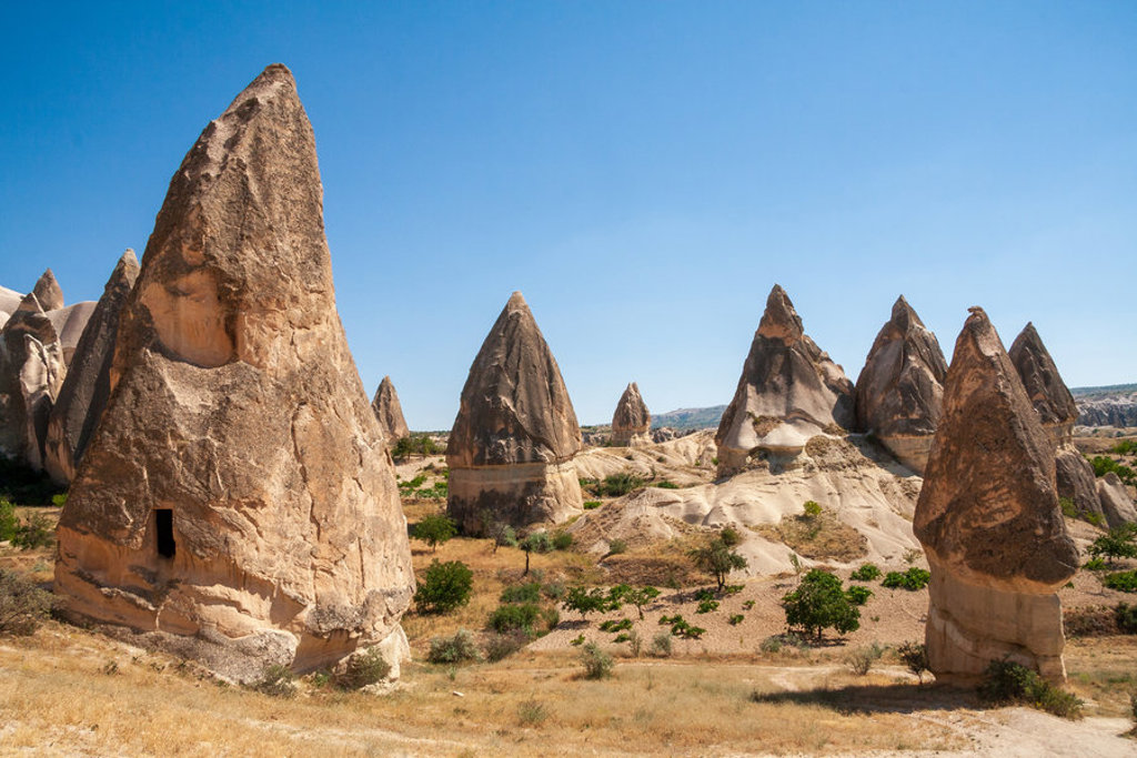 Rotsformaties in Cappadocië, Turkije, met puntige tufsteenpilaren onder een heldere blauwe lucht.