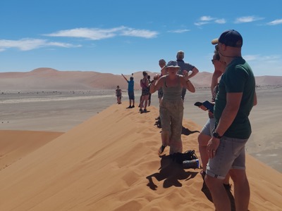 Reizigers lopen over een zandduin in de Namibwoestijn tijdens route Victoria Falls - Kaapstad.