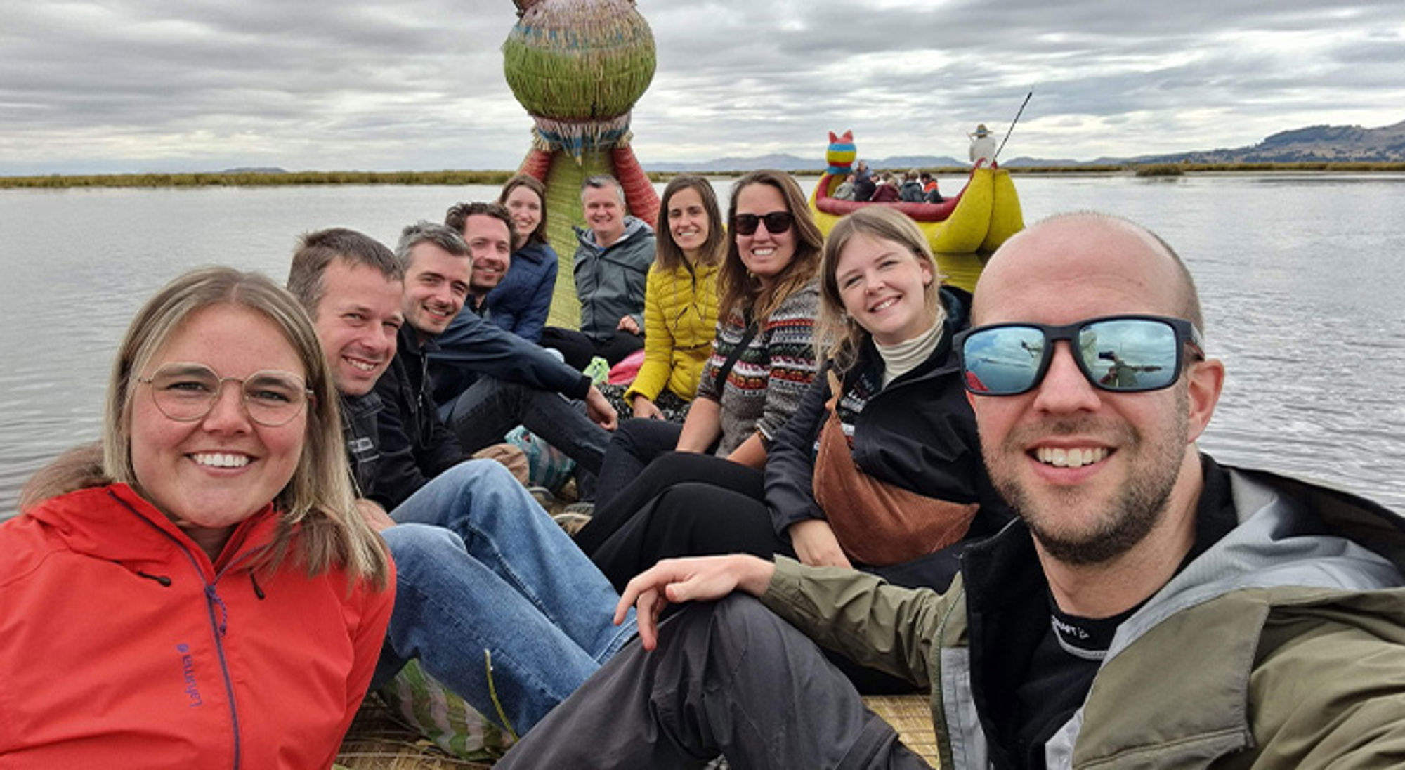 Titicacameer Groep reizigers op een rieten boot op het Titicacameer, met traditionele boot op de achtergrond.
