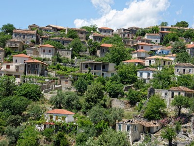 Heuveldorp in Albanië met stenen huizen en rode daken tussen groen, Route Albanië dag 6.
