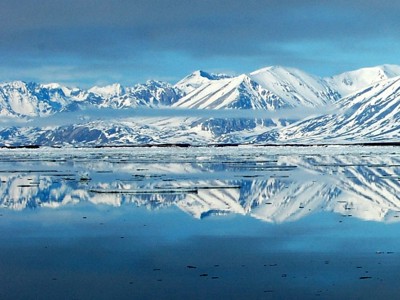 Besneeuwde bergketen weerspiegeld in een spiegelglad meer.