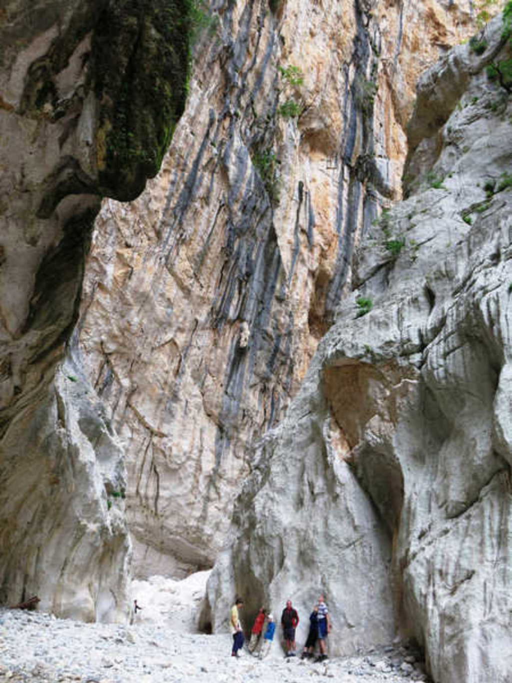 Wandelaars in een smalle kloof met hoge rotswanden op Sardinië, Italië.