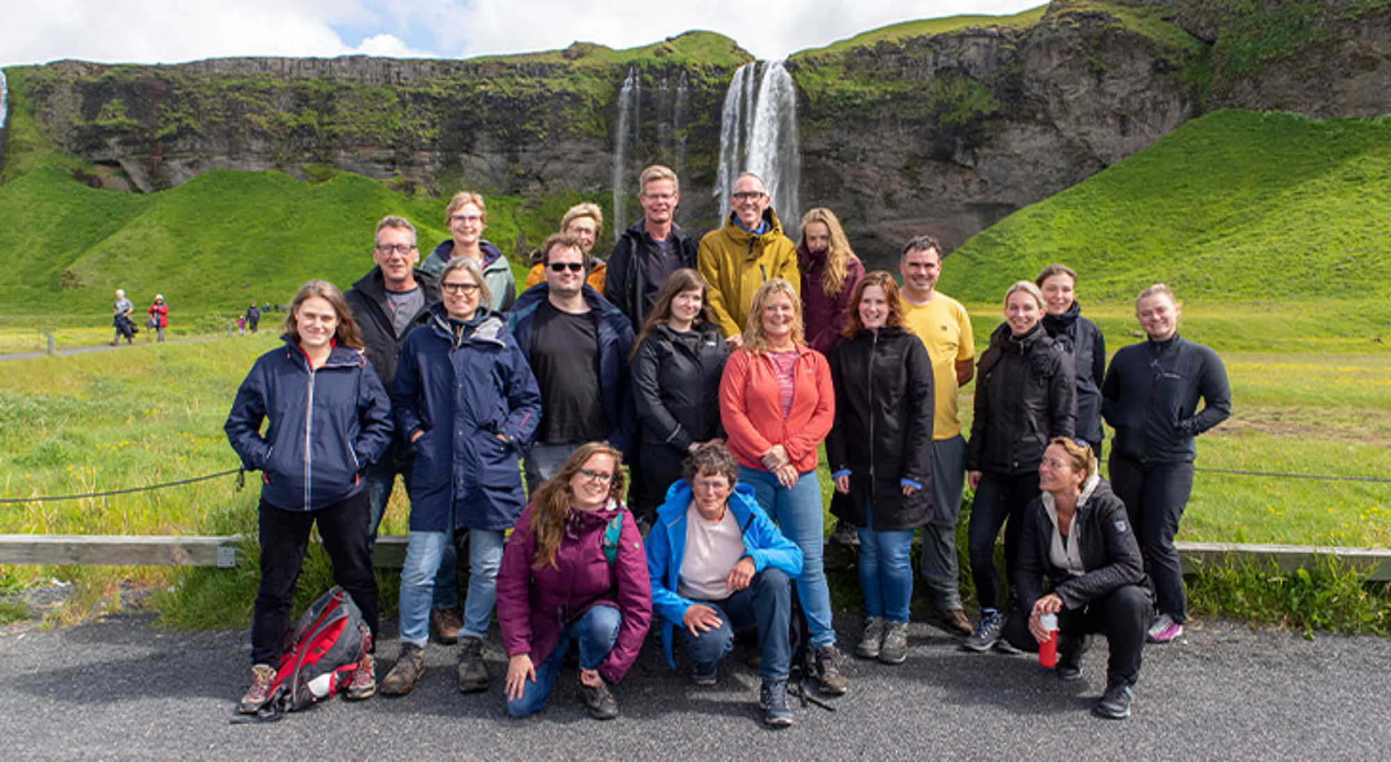 Groepsfoto van reizigers bij de Seljalandsfoss-waterval in IJsland.