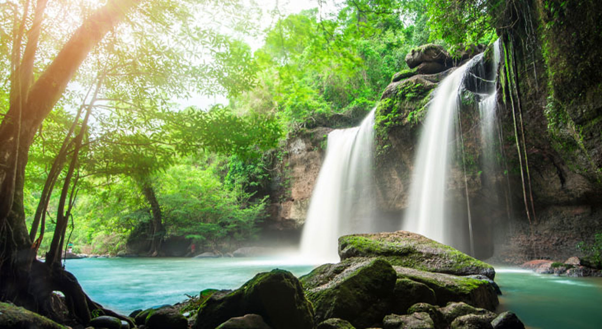 Waterval Khao Yai Waterval in een groene jungle in Thailand met turquoise water en rotsen op de voorgrond.