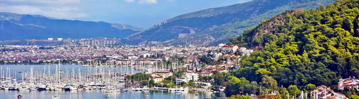 Uitzicht op de haven van Fethiye met zeilboten, stad en bergen aan de Turkse kust.