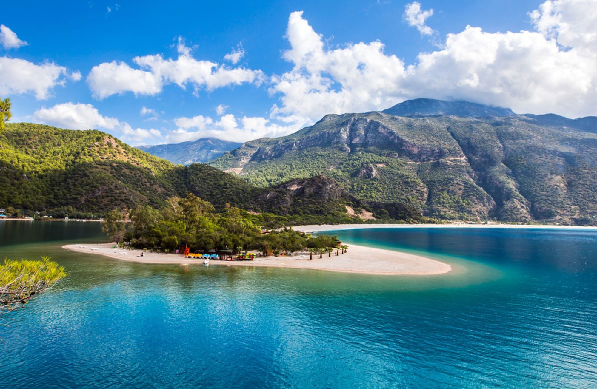 Groene heuvels en bergen bij een turkooizen lagune met zandbank en strand in Turkije.