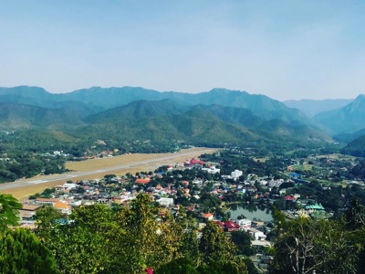 Uitzicht over Pai met landingsbaan, rivier en groene bergen in Noord-Thailand.