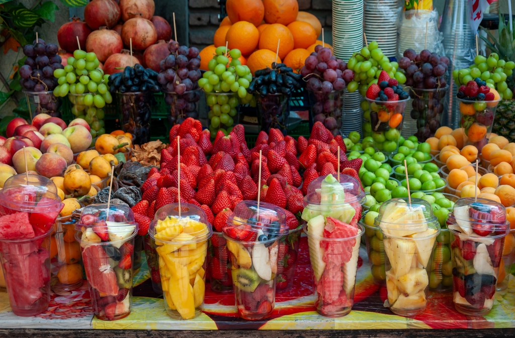 Kleurrijke fruitkraam op een markt in Georgië met druiven, aardbeien en vers fruit in bekers.
