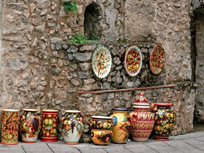 Handbeschilderd keramiek met fruitmotieven aan een stenen muur in de Amalfikust, Italië.