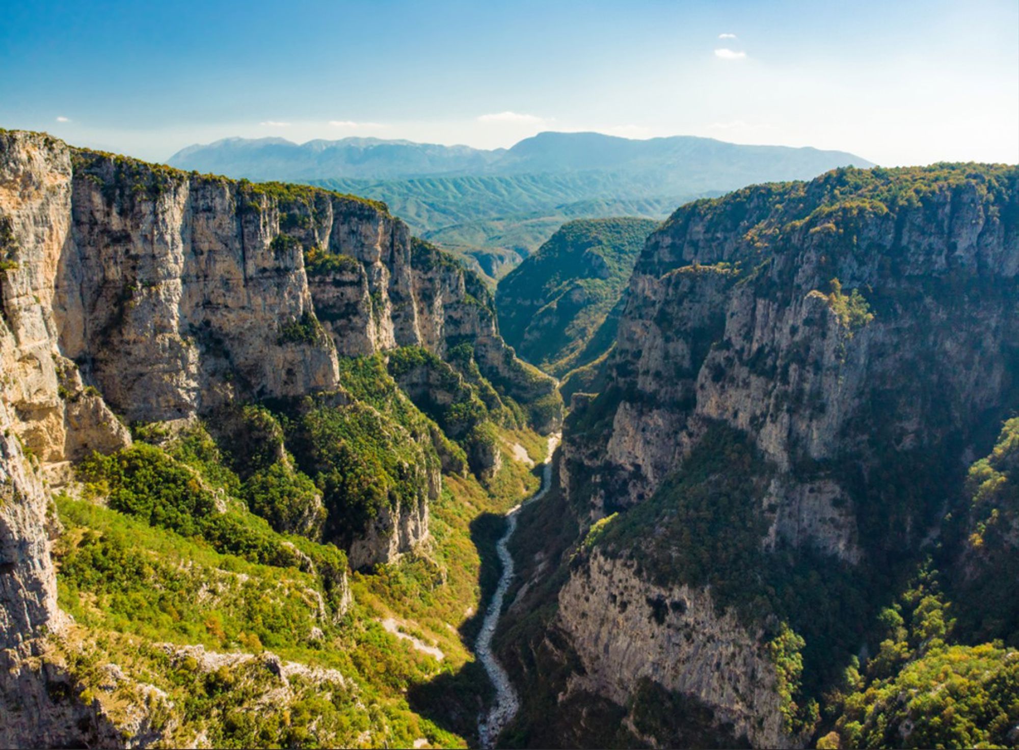 Uitzicht over de Vikos-kloof in Griekenland met steile rotswanden en een rivier in de vallei.