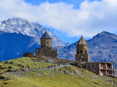 Gergeti Drievuldigheidskerk bij Kazbegi in Georgië, met besneeuwde bergtoppen op de achtergrond.
