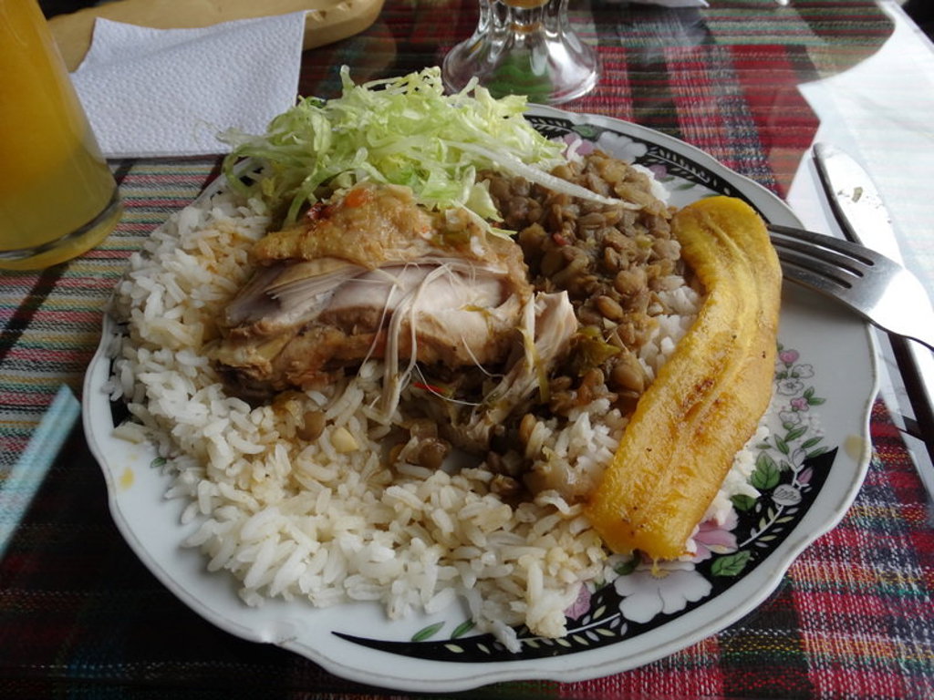 Traditionele maaltijd in Ecuador met rijst, linzen, kip en gebakken bakbanaan op een bord.