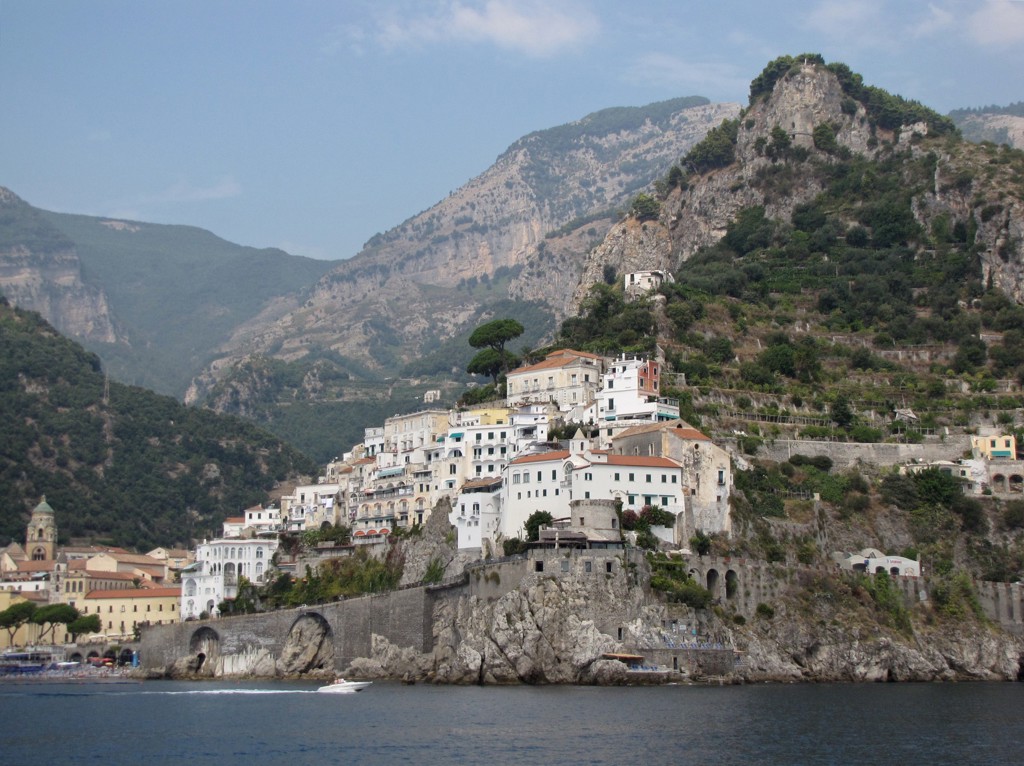 Kustplaats Amalfi aan de Amalfikust met witte huizen tegen de rotsen en bergen op de achtergrond.