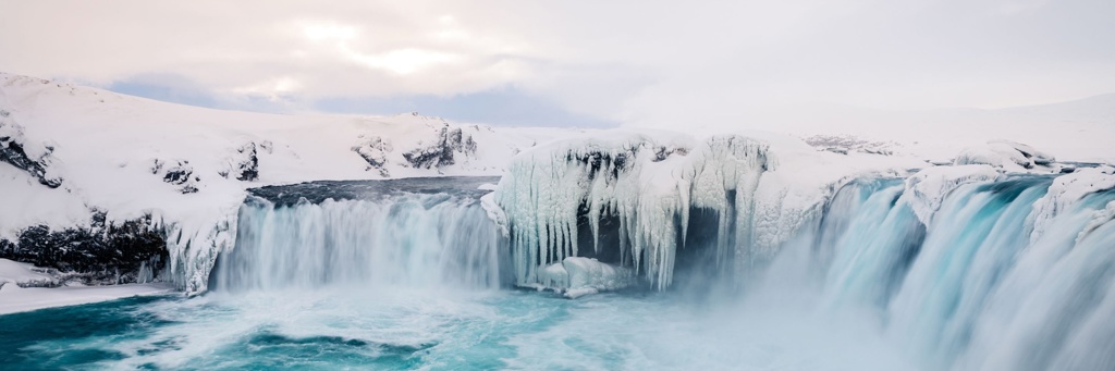 Bevroren waterval met ijspegels en turquoise water in Noord-IJsland.
