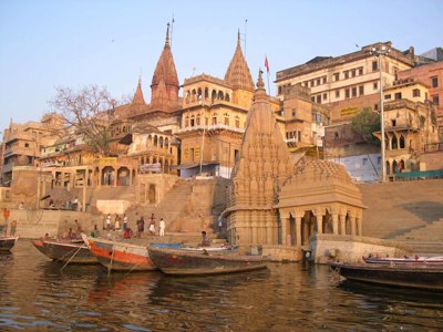 Tempels en ghats aan de Ganges in Varanasi, met boten aan de oever bij zonsondergang.