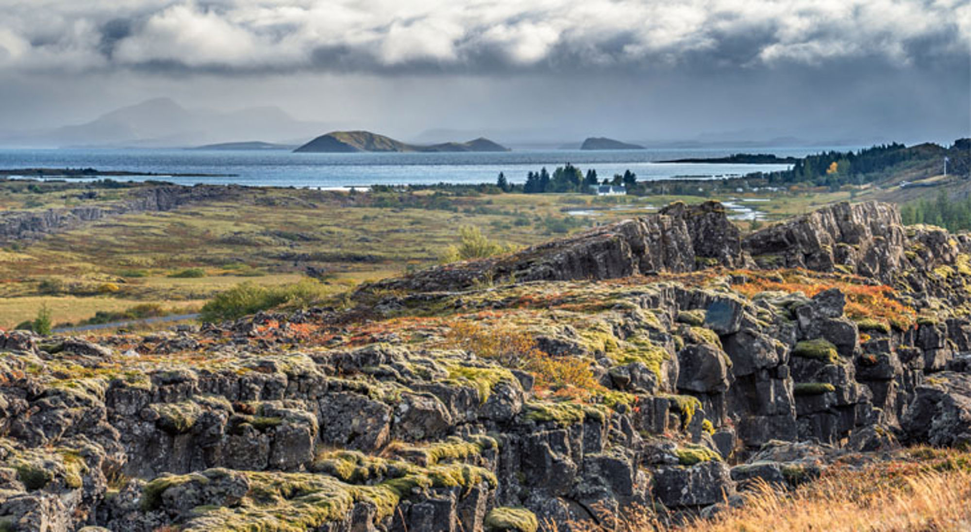 Park Þingvellir IJsland Uitzicht over het Þingvellir Nationaal Park in IJsland met rotskloven, mos en een meer onder bewolkte lucht.