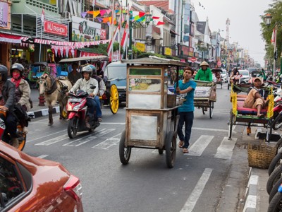 Drukke straat in Yogyakarta met straatverkoper, becaks en motoren tijdens de route Java en Bali.