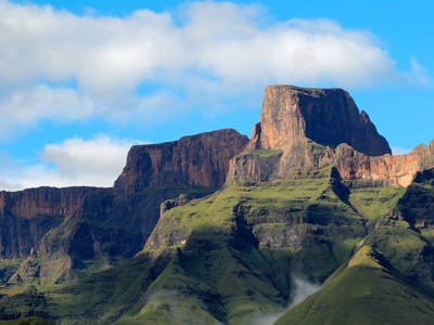 Groene bergtoppen en rotswanden in de Drakensbergen tijdens groepsrondreis Zuid-Afrika van Johannesburg naar Kaapstad.