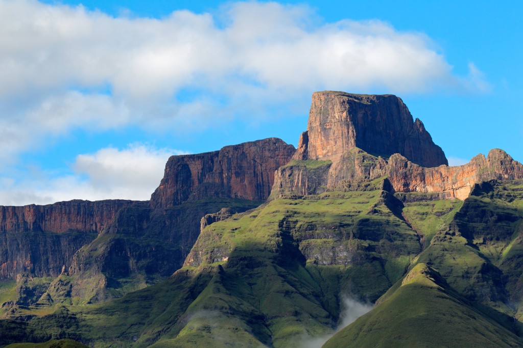 Groene bergtoppen en rotswanden in de Drakensbergen tijdens groepsrondreis Zuid-Afrika van Johannesburg naar Kaapstad.