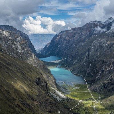 Bergvallei in Noord-Peru met turquoise meren, steile rotswanden en een slingerende weg onder wolkenlucht.