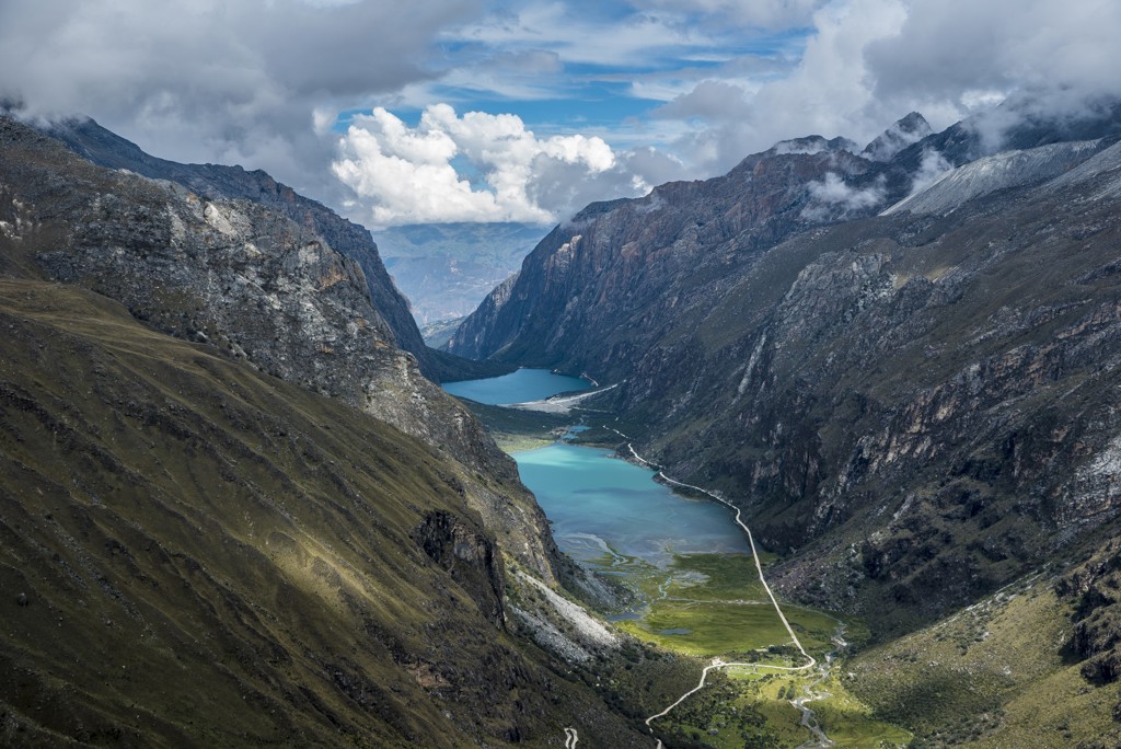 Bergvallei in Noord-Peru met turquoise meren, steile rotswanden en een slingerende weg onder wolkenlucht.