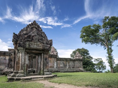 Ingang van een eeuwenoude Khmer-tempel in Cambodja, met stenen reliëfs onder een blauwe lucht.