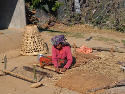 Vrouw weeft een rieten mat in een Nepalees dorp tijdens de Route Nepal Familiereis 15 dagen, .