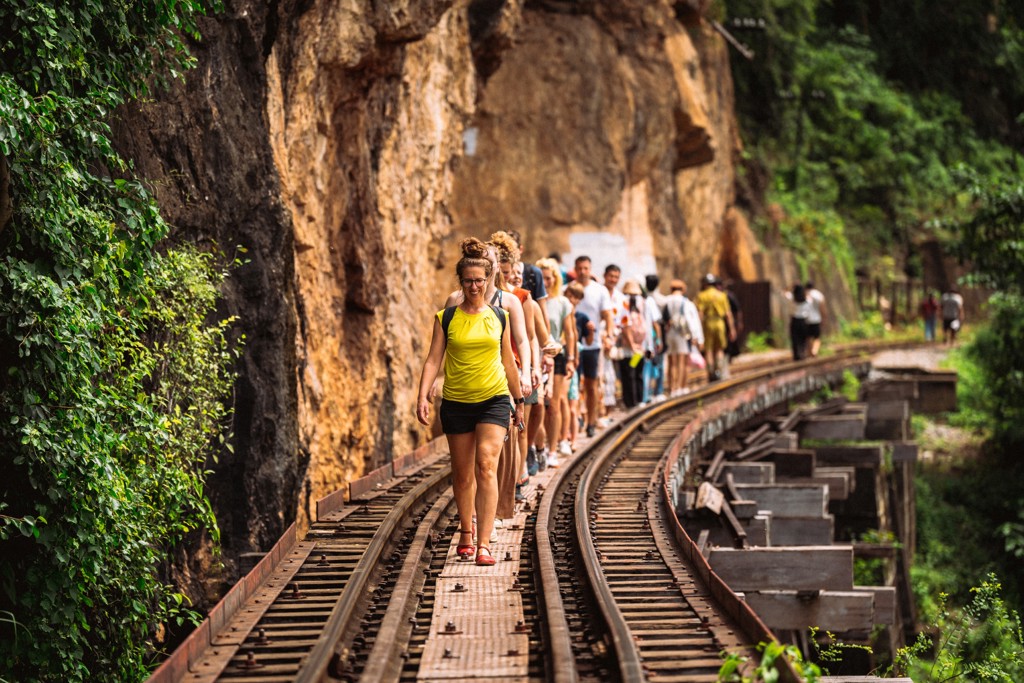 Groepsrondreis Thailand: reizigers wandelen over de Death Railway langs een rotswand bij Kanchanaburi.