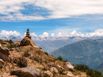 Steenmannetje op een rots met uitzicht over de Andes in Peru.