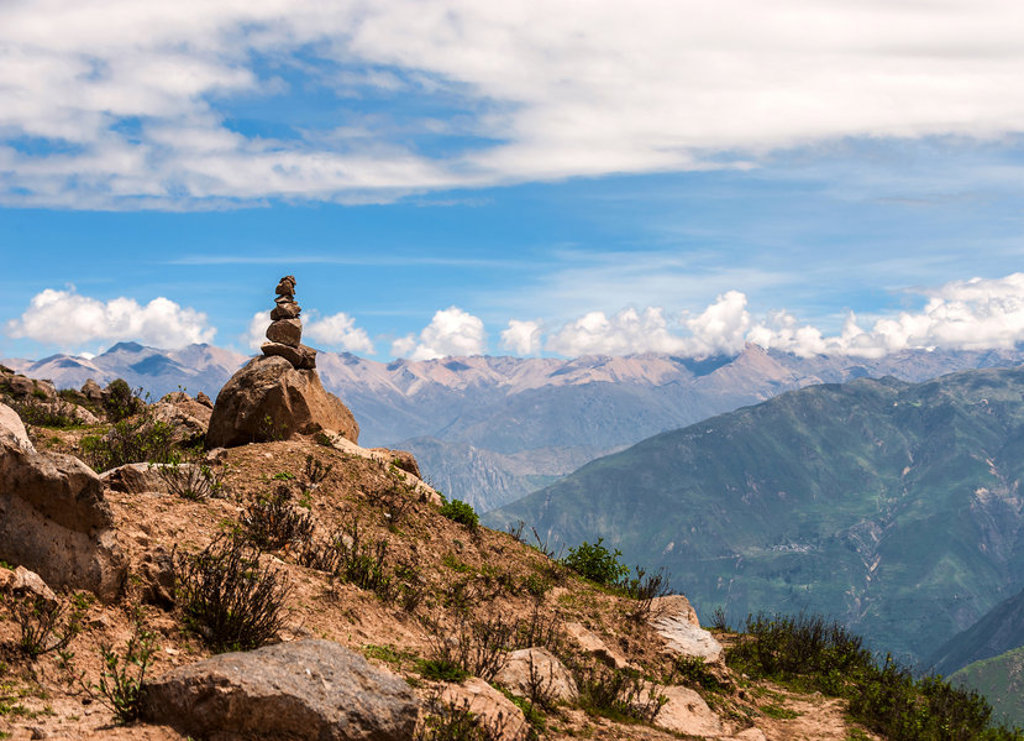 Steenmannetje op een rots met uitzicht over de Andes in Peru.