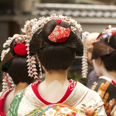Japanse vrouwen in kleurrijke kimono’s met traditionele haaraccessoires, gezien van achteren.
