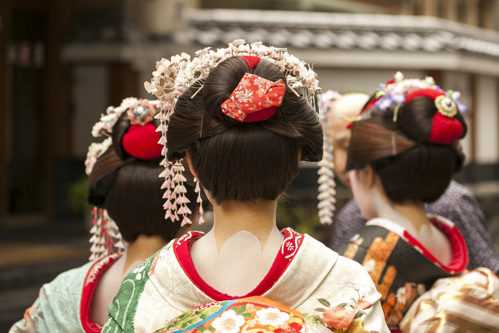 Japanse vrouwen in kleurrijke kimono’s met traditionele haaraccessoires, gezien van achteren.