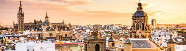 Skyline van Sevilla bij zonsondergang met de Giralda-toren en de koepel van de Catedral de Sevilla.
