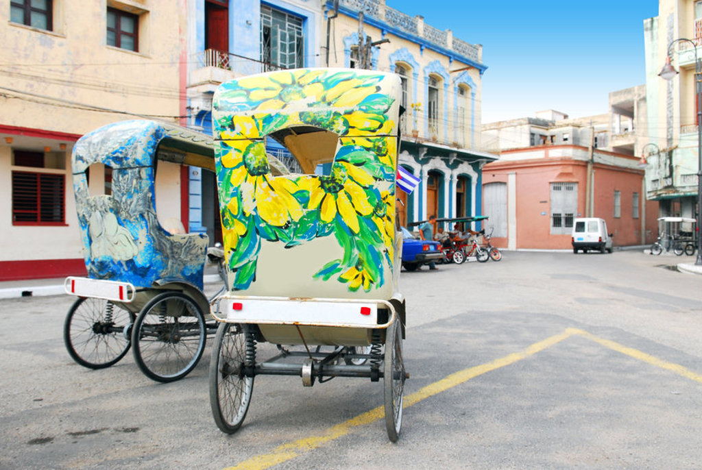 Fel beschilderde fietstaxi’s in een straat in Cuba, tijdens een familiereis.