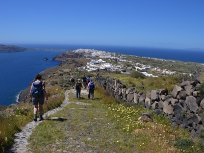 Wandelaars op een kustpad met uitzicht op de witte dorpjes en de caldera van Santorini.